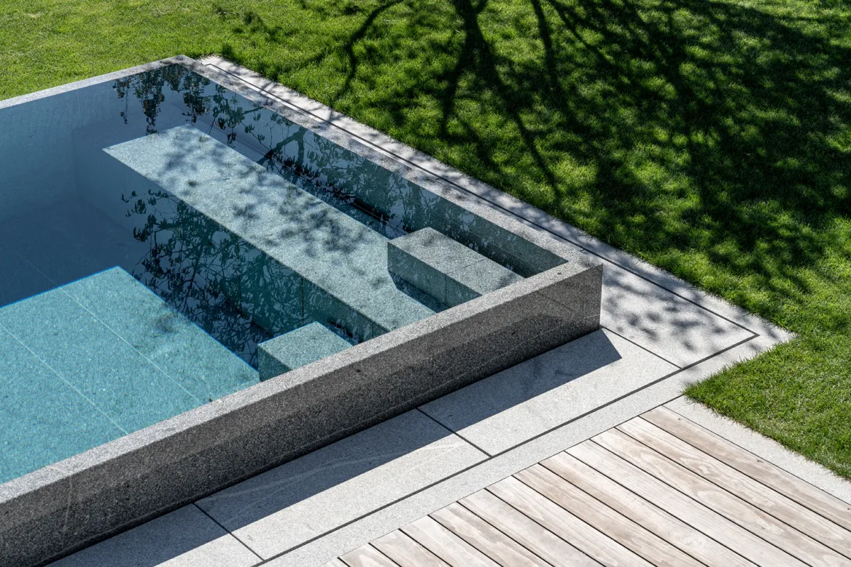 Natursteinpool mit Blockstufentreppe und integrierter Rolladenabdeckung