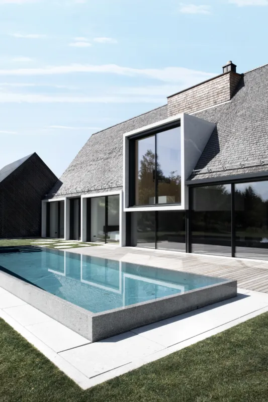 Schwimmbecken gefertigt aus massivem Granit vor einem architektonisch schönem Haus
