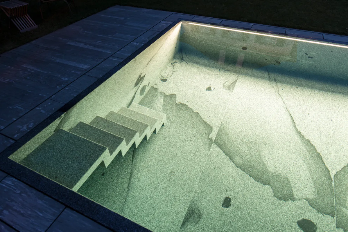 Poolbeleuchtung eines Natursteinbecken bei Nacht