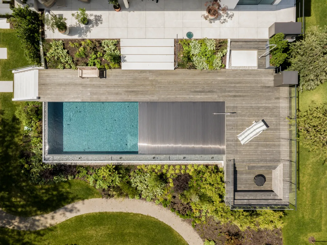 Drohnenbild eines Natursteinpools mit halb geschlossenerer Rollladenabdeckung