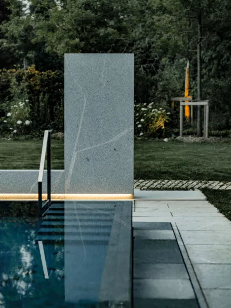Eine Outdoordusche aus massiven Granit bei Nacht